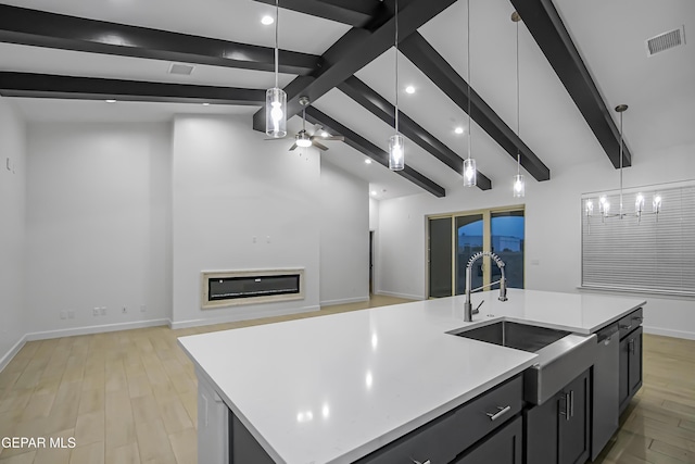 kitchen with pendant lighting, dishwasher, light wood-type flooring, and a large island with sink