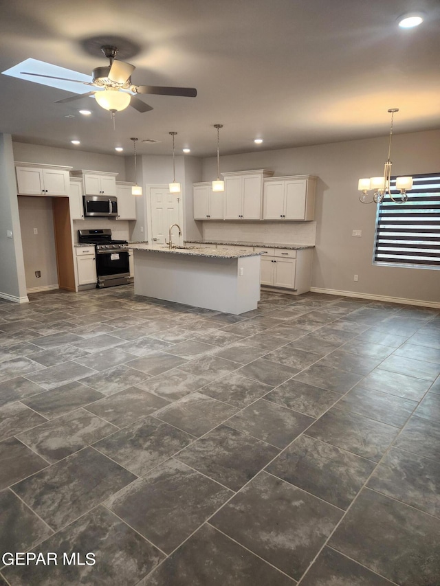 kitchen with appliances with stainless steel finishes, a skylight, sink, and dark tile patterned floors