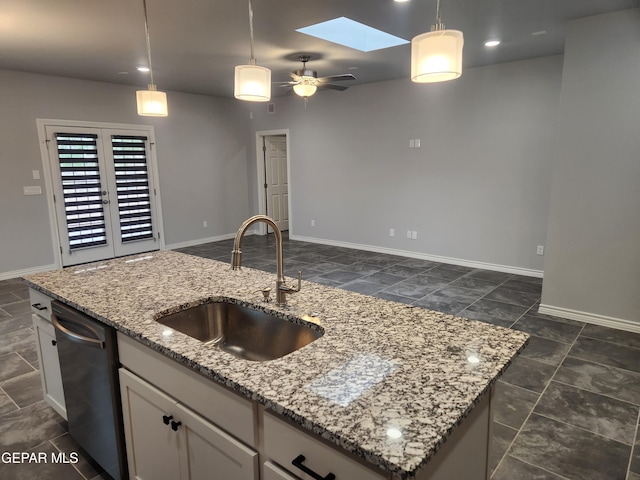 kitchen with dark tile patterned flooring, a skylight, dishwashing machine, ceiling fan, and sink