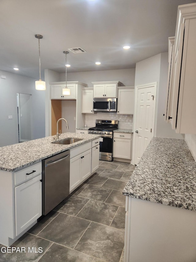 kitchen with decorative backsplash, white cabinetry, appliances with stainless steel finishes, an island with sink, and sink