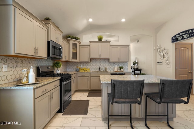 kitchen featuring decorative backsplash, vaulted ceiling, light tile patterned floors, and stainless steel appliances