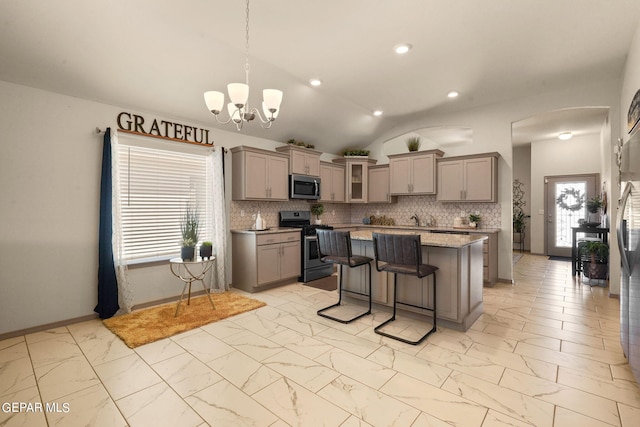 kitchen with decorative backsplash, lofted ceiling, appliances with stainless steel finishes, and light tile patterned flooring