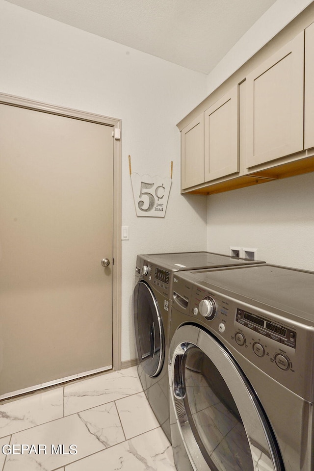 washroom featuring cabinets, light tile patterned flooring, and washer and clothes dryer