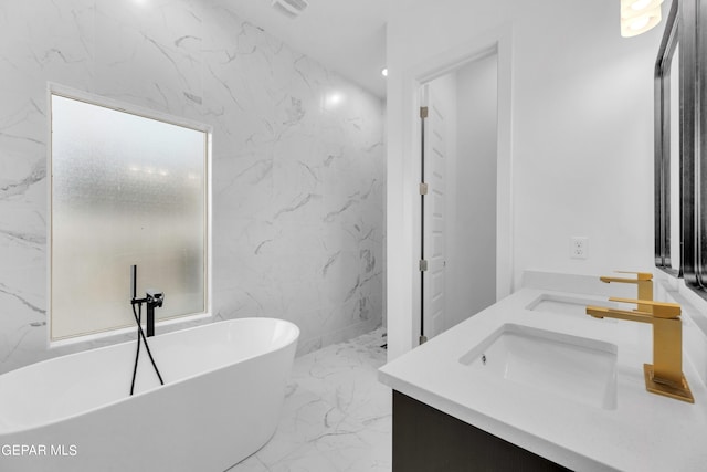 bathroom with tile walls, double sink vanity, a bathtub, and tile patterned flooring