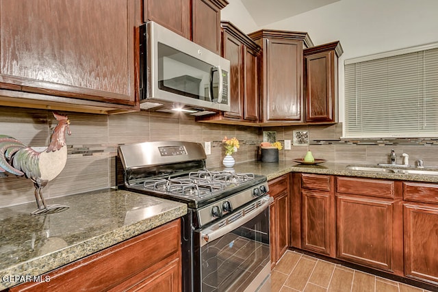 kitchen with sink, decorative backsplash, dark stone counters, and stainless steel appliances