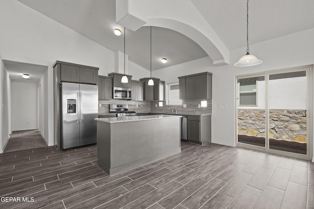 13158 Ludlow Ln, El Paso, TX 79928 - kitchen with appliances with stainless steel finishes, wood tiled floors, high vaulted ceiling, a kitchen island, and tasteful backsplash