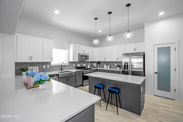 kitchen featuring sink, white cabinetry, appliances with stainless steel finishes, a center island, and a breakfast bar area