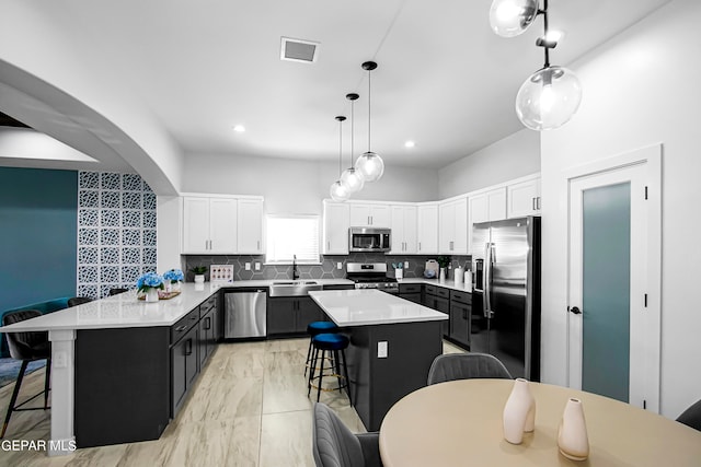 kitchen featuring a kitchen bar, a center island, stainless steel appliances, and kitchen peninsula