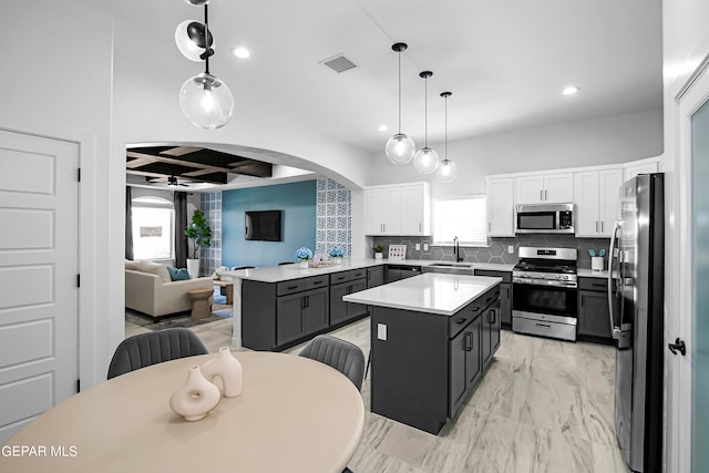 kitchen with stainless steel appliances, white cabinets, a wealth of natural light, and a center island