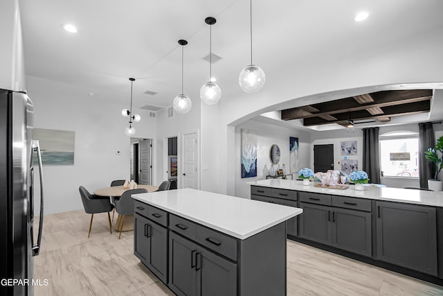 kitchen featuring ceiling fan, pendant lighting, stainless steel fridge, gray cabinetry, and a center island