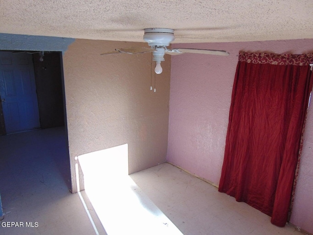 unfurnished room with ceiling fan and a textured ceiling