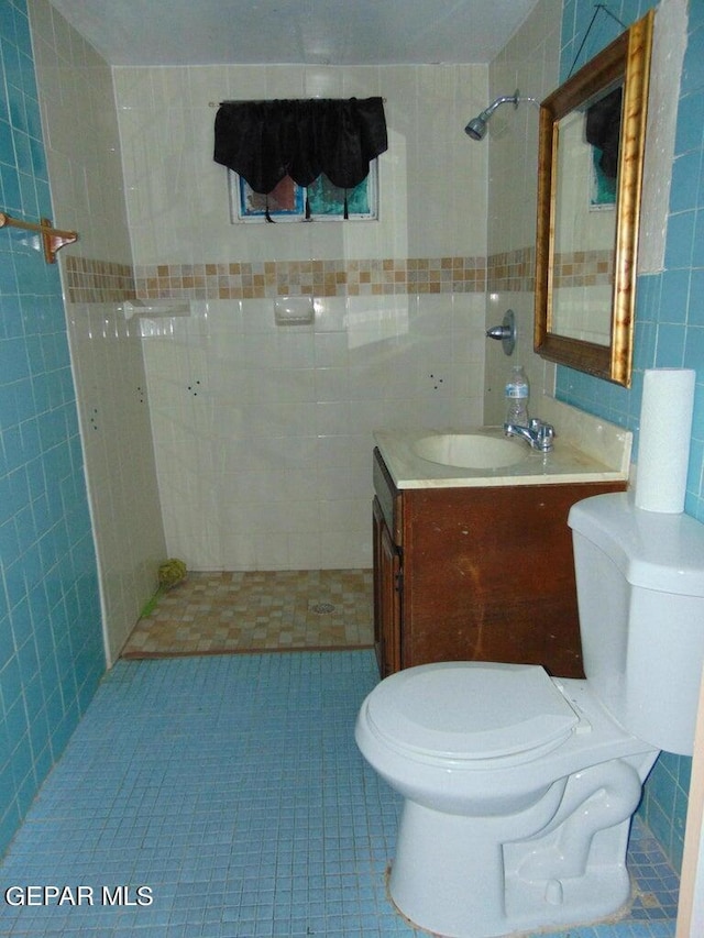 bathroom featuring tile patterned floors, vanity, tiled shower, and toilet