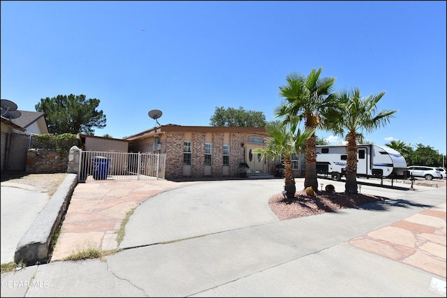 view of front of home featuring a gate, brick siding, driveway, and fence