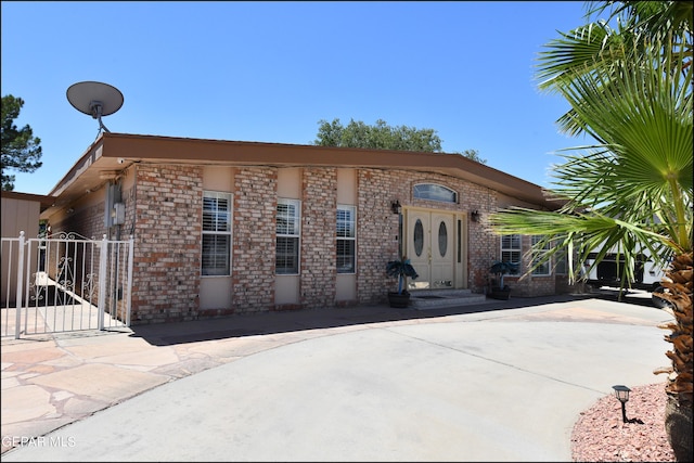 view of front facade with a gate, brick siding, and fence