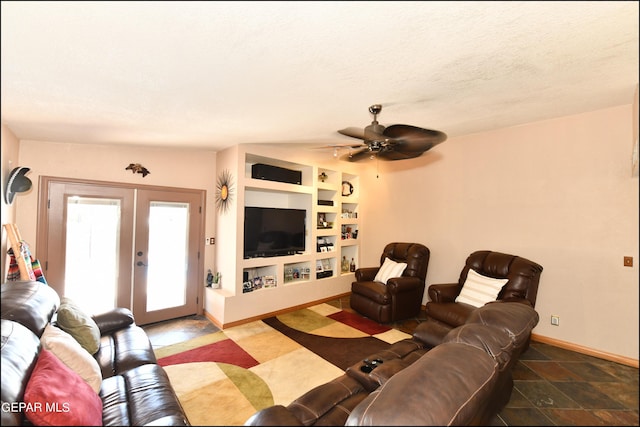 living area with a textured ceiling, built in shelves, a ceiling fan, baseboards, and french doors