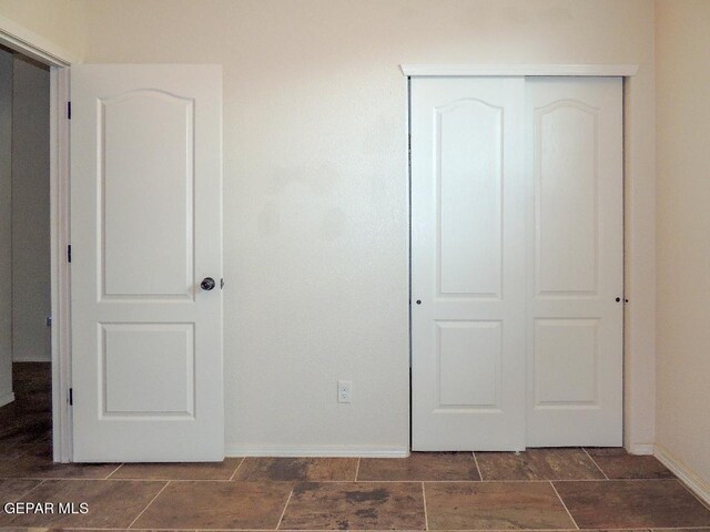 unfurnished bedroom with dark tile patterned flooring and a closet