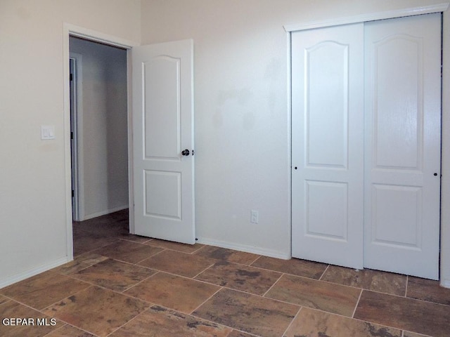 unfurnished bedroom featuring a closet and dark tile patterned floors