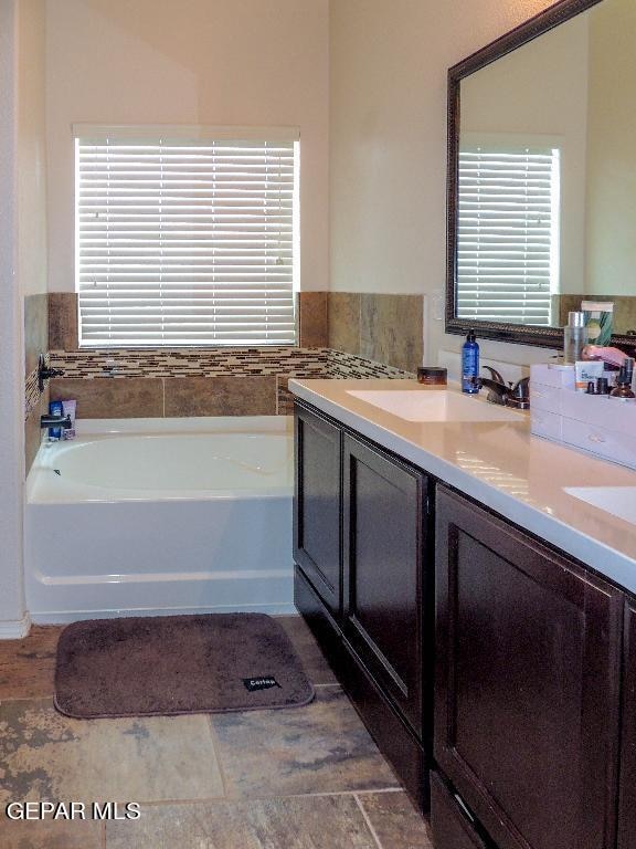 bathroom featuring tile patterned floors, a tub to relax in, and vanity