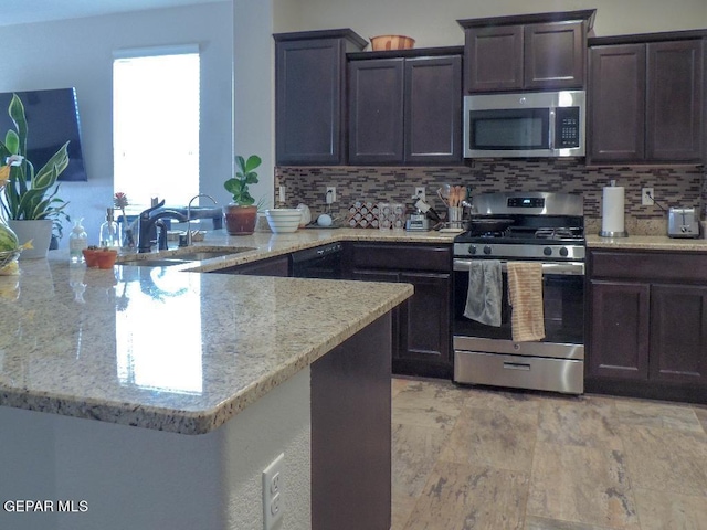 kitchen with tasteful backsplash, appliances with stainless steel finishes, light stone counters, kitchen peninsula, and dark brown cabinets