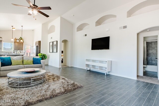 living room featuring ceiling fan, high vaulted ceiling, and dark wood-type flooring