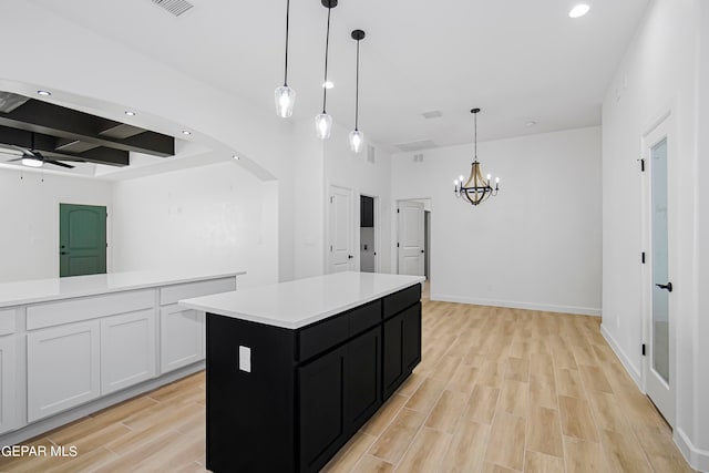 kitchen featuring light hardwood / wood-style floors, a center island, ceiling fan with notable chandelier, white cabinetry, and decorative light fixtures