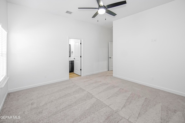 spare room featuring light carpet, ceiling fan, and a wealth of natural light