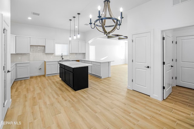 kitchen featuring light hardwood / wood-style flooring, white cabinets, hanging light fixtures, and a kitchen island