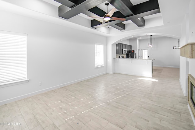 unfurnished living room featuring beamed ceiling, light hardwood / wood-style floors, ceiling fan, and coffered ceiling