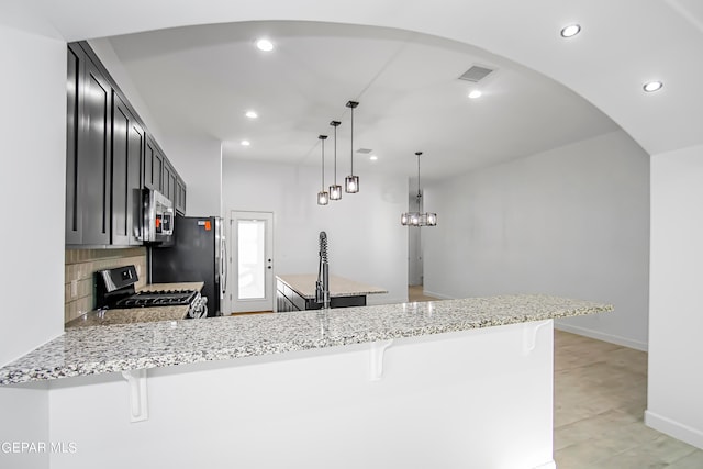 kitchen with a kitchen bar, stainless steel appliances, hanging light fixtures, and kitchen peninsula