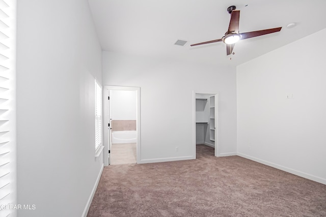 unfurnished bedroom featuring a closet, light carpet, connected bathroom, a spacious closet, and ceiling fan