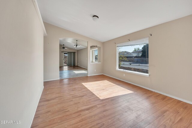 empty room with ceiling fan, lofted ceiling, and light wood-type flooring