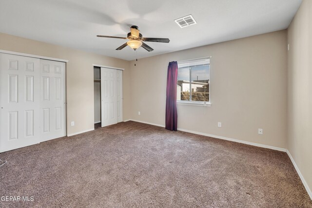 unfurnished bedroom featuring carpet floors, ceiling fan, and two closets