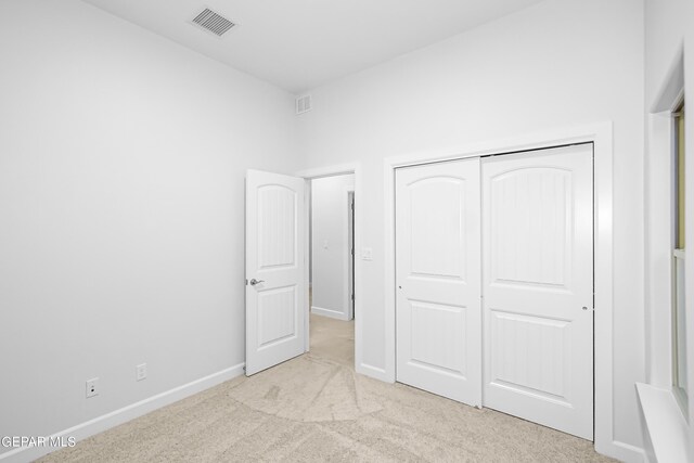 unfurnished bedroom with light carpet and a closet