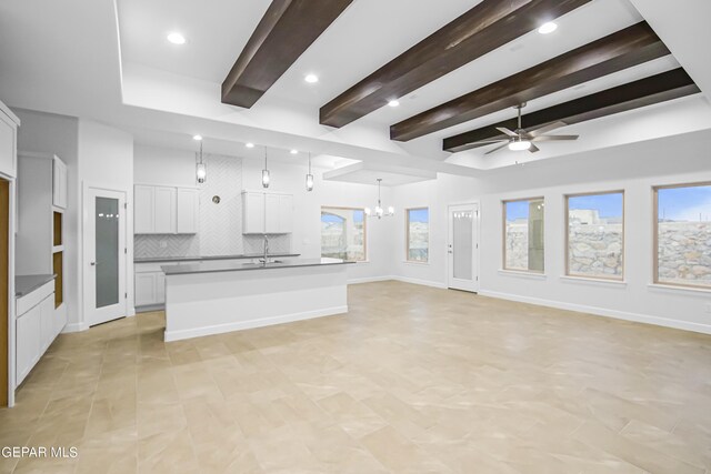 unfurnished living room featuring ceiling fan with notable chandelier, beam ceiling, and sink