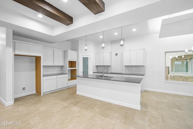 kitchen with white cabinetry, tasteful backsplash, decorative light fixtures, a center island with sink, and sink