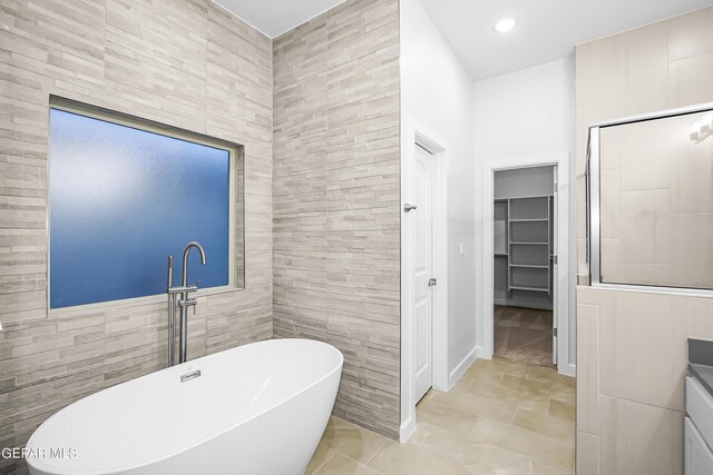 bathroom with shower with separate bathtub, tile walls, and vanity