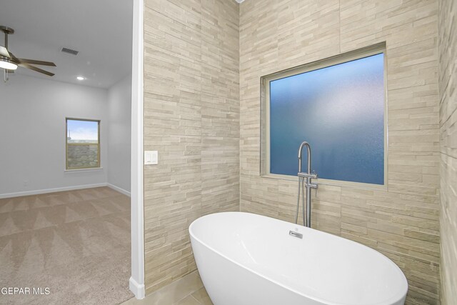 bathroom with tile walls, a tub to relax in, and ceiling fan