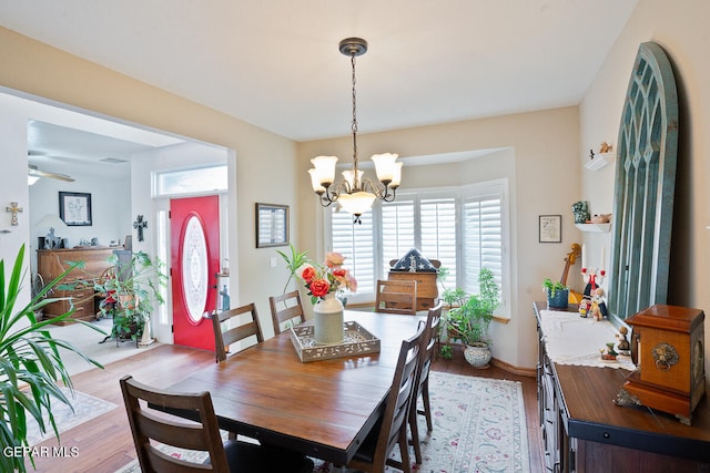 dining space with ceiling fan with notable chandelier and light hardwood / wood-style flooring