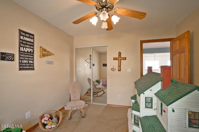 recreation room with ceiling fan, a textured ceiling, and carpet flooring