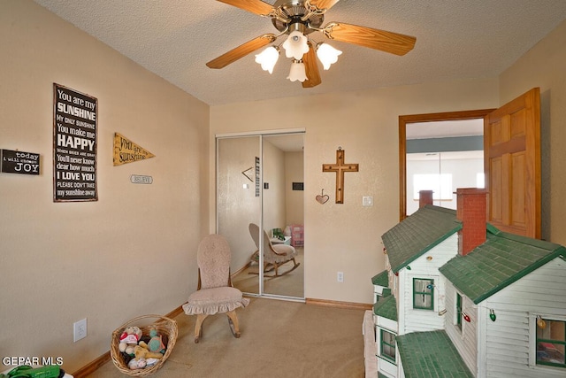 playroom with carpet, ceiling fan, a textured ceiling, and baseboards