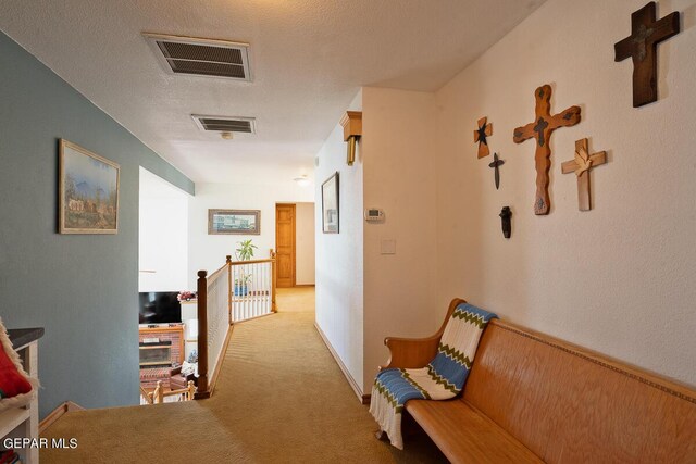 hall featuring a textured ceiling and light carpet