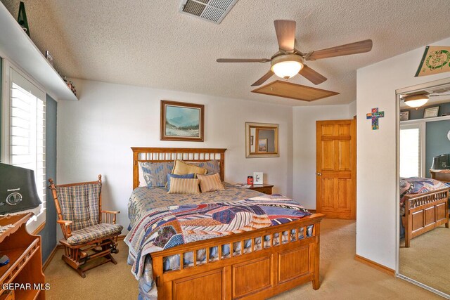 bedroom featuring ceiling fan, light colored carpet, and a textured ceiling