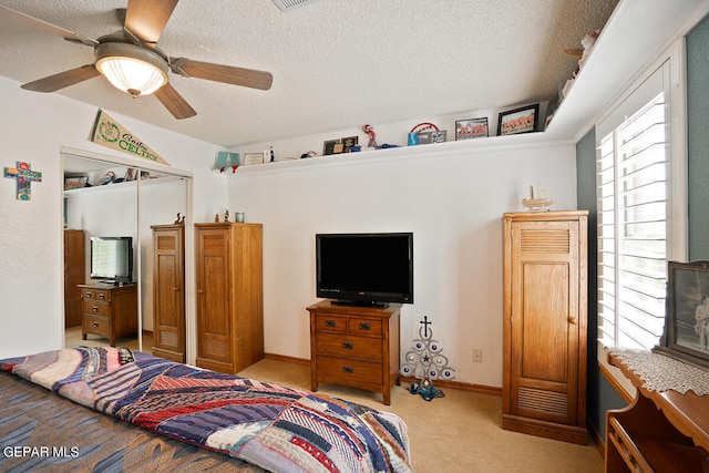 carpeted bedroom with a closet, ceiling fan, and a textured ceiling