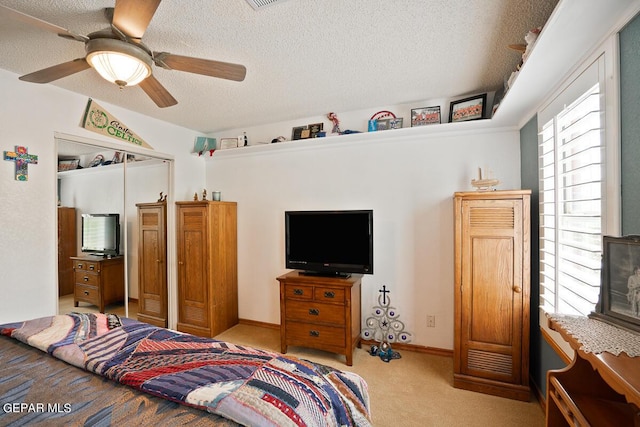 bedroom with a closet, a ceiling fan, carpet flooring, a textured ceiling, and baseboards