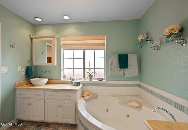 bathroom featuring tiled tub and vanity