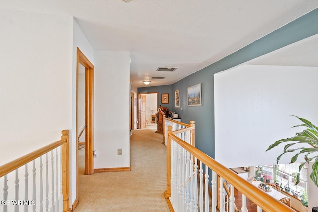 corridor with baseboards, light colored carpet, visible vents, and an upstairs landing