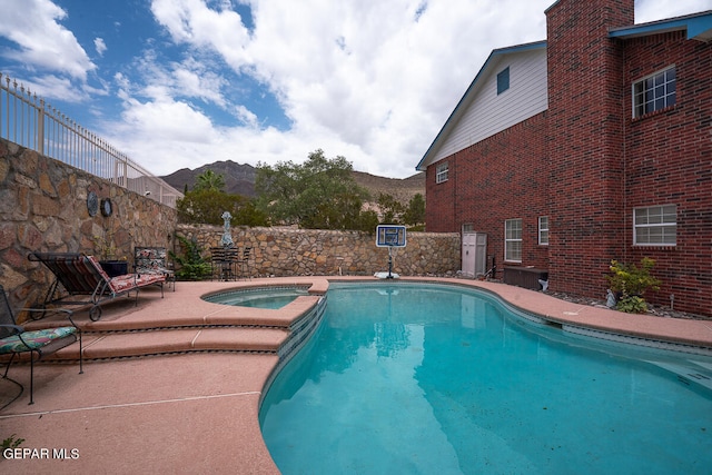 view of swimming pool with a patio, a mountain view, and an in ground hot tub