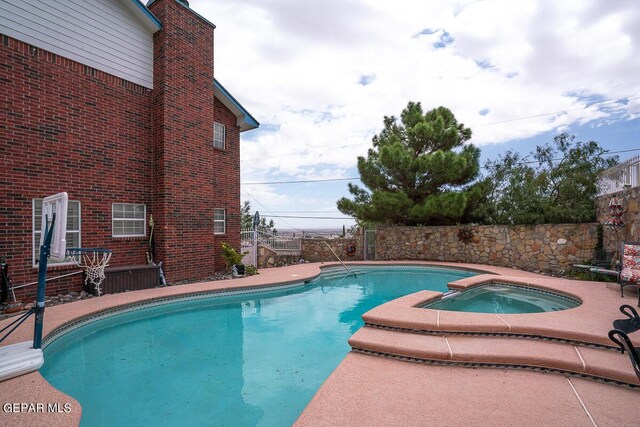 view of swimming pool featuring a pool with connected hot tub and a fenced backyard