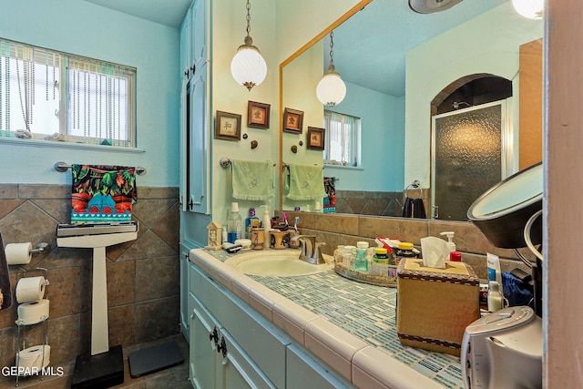 full bath featuring a wealth of natural light, wainscoting, tile walls, and a stall shower