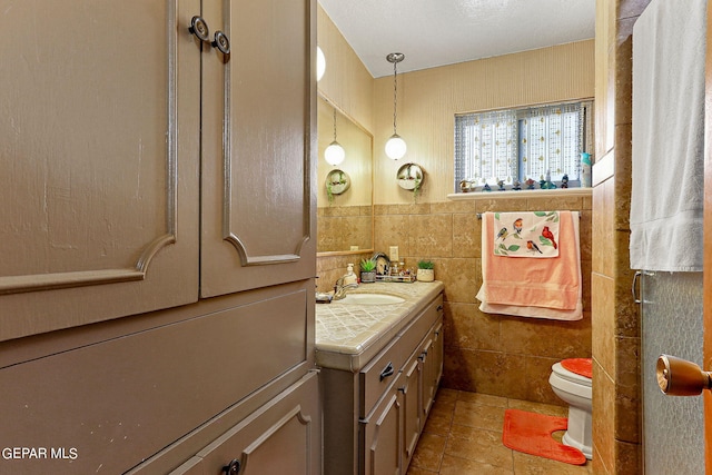 bathroom with toilet, tile walls, and vanity